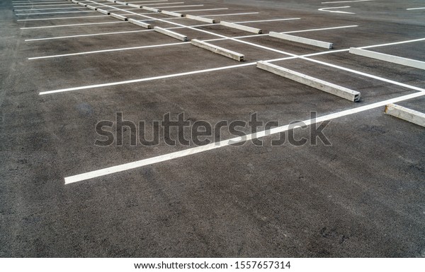 Empty asphalt parking lot with concrete car\
stopper, perspective\
view.