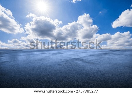 Empty asphalt pavement background under a bright sunny sky with clouds, ideal for car product placement.