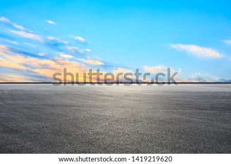 Empty asphalt race track and sunset sky