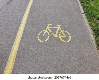 Empty Asphalt Road In City Park With Separate Way For Bicycle, Marked With Bike Sign At Daytime. With No People, Safe Urban Environment Background.