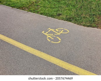 Empty Asphalt Road In City Park With Separate Lane For Bicycle, Marked With Bike Sign At Daytime. With No People, Safe Urban Environment Background.