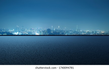 Empty asphalt road with city skyline background, night scene - Powered by Shutterstock