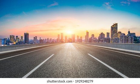 Empty asphalt road and city skyline with buildings at sunset in Shanghai.