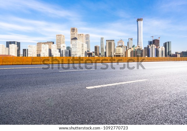 empty asphalt road with\
city skyline