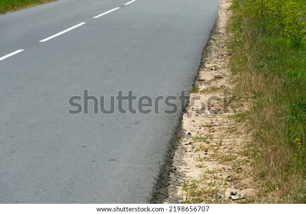 Empty\
asphalt road close-up against the sky. Empty background, space for\
text. New asphalt concrete pavement in rural\
areas.
