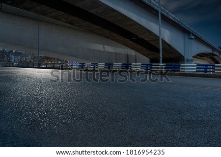 empty asphalt road in downtown under bridge at night.