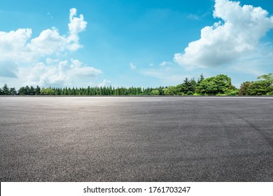 Empty asphalt road and green forest under blue sky.