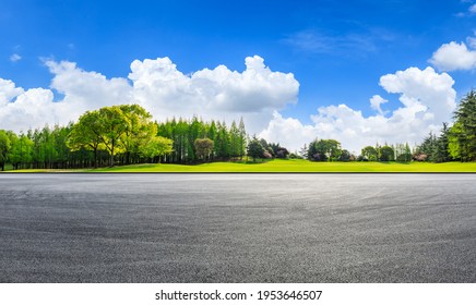 Empty asphalt road and green forest under blue sky.