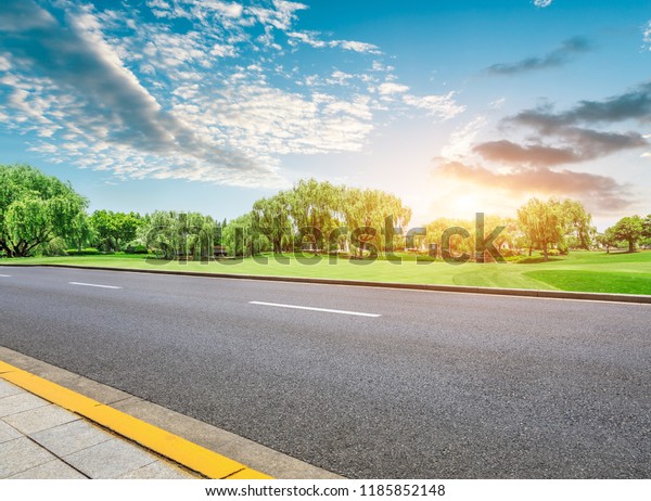 Empty asphalt road and green forest with colorful
clouds at sunset