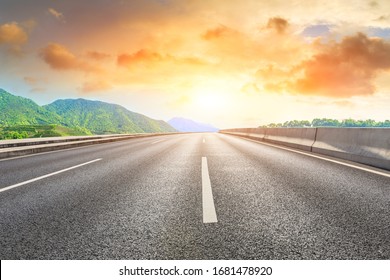 Empty asphalt road and green mountain nature landscape at sunset.