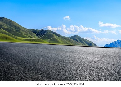 Camino asfalto vacío y montaña verde bajo cielo azul