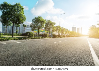 Empty Asphalt Road In Modern City At Sunrise