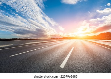 Empty asphalt road and mountain with colorful sky clouds at sunrise