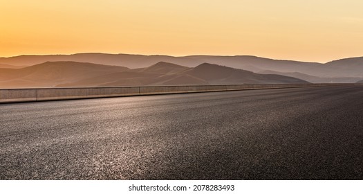 Empty asphalt road and mountain scenery at sunrise - Shutterstock ID 2078283493