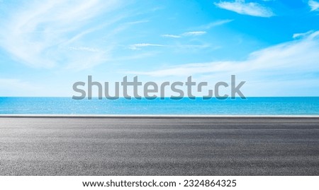 
Empty asphalt road near beach under blue sky