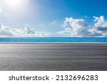 Empty asphalt road near the lake under blue sky