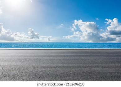 Empty asphalt road near the lake under blue sky