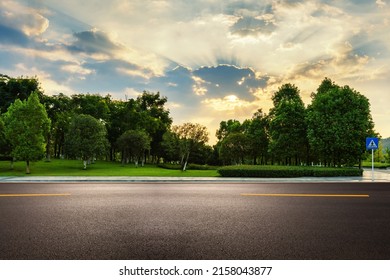 empty asphalt road near park with explosive sunshine in the sky during sunrise.