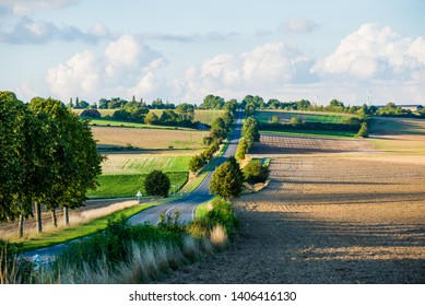 An empty asphalt road through the country fields. Clear sunny day. Normandy, France - Shutterstock ID 1406416130