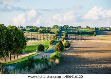 An empty asphalt road through the country fields. Clear sunny day. Normandy, France