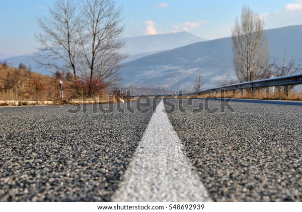 Empty asphalt road with white line in the\
middle of the road; asphalt road in the mountain on sunny autumn\
day; selective focus\
background.