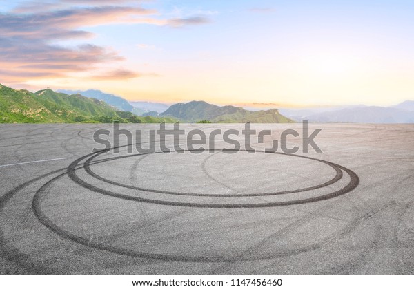 Empty asphalt square car tire brakes and mountain\
scenery at sunrise