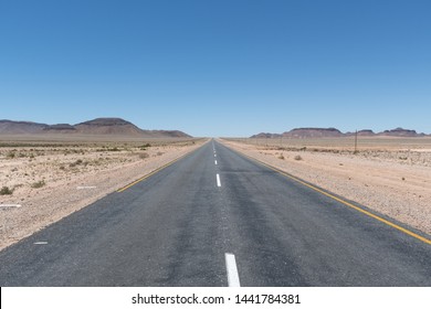 An empty asphalted and seemingly endless road that stretches through the Namibian wasteland on its way to the Fish River Canyon to the horizon.