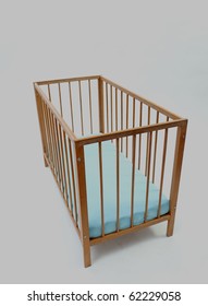 Empty Baby Wooden Cot With Blue Mattress