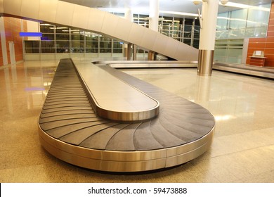Empty Baggage Carousel In Airport Hall With Granite Floor And Glass Walls