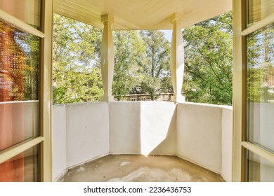 an empty balcony with trees in the background and sun shining through the glass doors on the second floor to the patio
