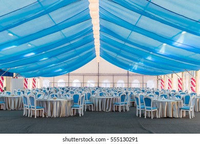 An Empty Banquet Hall. Big Tent With Blue Curtains, Tables And Chairs For A Large Number Of Guests. Holiday Decoration, Dinner Party.