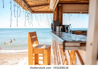 An empty bar counter and an empty chair against the background of the beach and the sea. Vacation and summer.