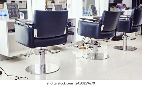 An empty barber chair with cut hair around it at hair salon. Hair on floor around chair. Interior of a Hairdressing Salon. - Powered by Shutterstock