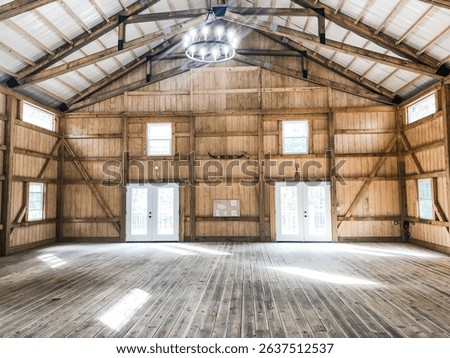 Empty barn with high ceilings and rustic chandelier with light coming through the windows