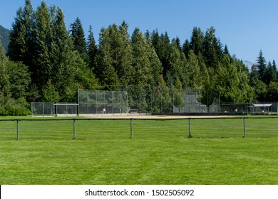 Empty baseball or softball diamond from the back fence and foul line looking towards the grass and trees in Whistler, British Columbia, Canada.