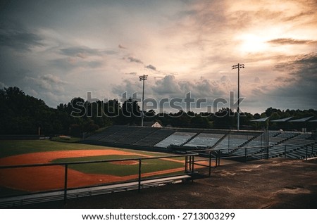 Empty baseball stadium stands and field at dawn, capturing a moody, nostalgic atmosphere. Ideal for sport, community, and summer themes with dramatic light.