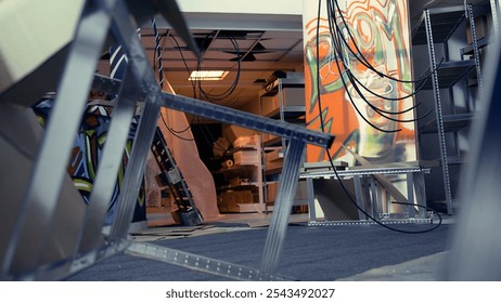 Empty basement with damaged objects and graffiti paint, concept of subversive lifestyle. Criminal hideout used by juvenile delinquents to commit illegal activities, handheld camera shot