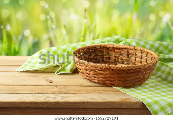 Empty basket with\
tablecloth on wooden table over green bokeh background. Spring and\
easter mock up for\
design.
