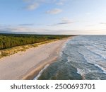 Empty beach at the Baltic Sea, grasses against a background of the setting sun, waves and the sea