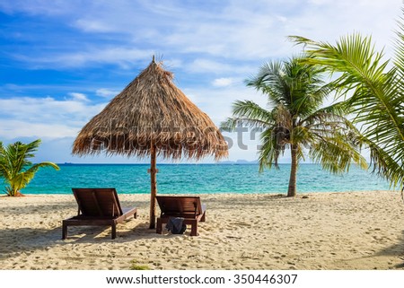 Empty beach bed under thatched umbrellas on a sandy beach