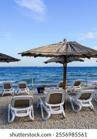 Empty beach cafe without visitors after the end of the season, reed sunshades, empty sunbeds, Adriatic Sea, Croatia