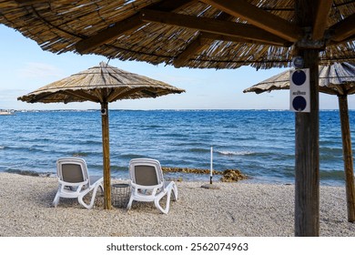 Empty beach cafe without visitors after the end of the season, reed sunshades, empty sunbeds, Adriatic Sea, Croatia