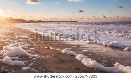 empty beach with foam of the waves in Saint Clément des Baleines, in the distance the whale lighthouse at sunset on the Ile de Ré in France