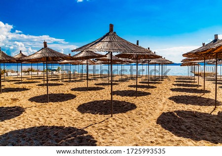 Empty beach with reed beach umbrellas, nobody on the beach. Beautiful blue sky, hot weather. Beach with no travellers and tourists. Cancellations due to coronavirus covid-19. Quarantine.