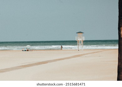 Empty beach with white lifeguard station on a horizon by a blue mediterranean sea. Wooden hut on morning sandy beach. Wooden path leads to the water.  - Powered by Shutterstock