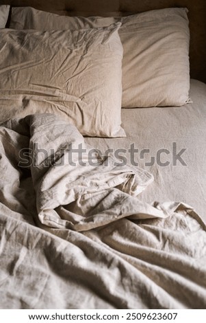 Empty bed covered wrinkled bedding and pillows in cozy bedroom at nighttime.
