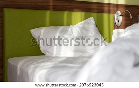 Empty bed with disheveled pillow and sheets. Dirty bed with decorate room.