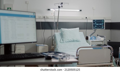 Empty Bed In Hospital Ward With Medical Equipment For Healthcare And Recovery. Nobody In Reanimation Room With Heart Rate Monitor And IV Drip Bag For Intensive Care And Assistance.