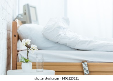 empty bed, orchids and glass of water in hospital ward
