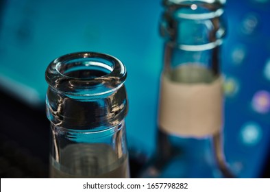 Empty Beer Bottles, Upper Part, In Front Of A Switched On Momitor. Selective Focus. Concept For Alcohol Abuse And Alcohol Dependency At The Workplace